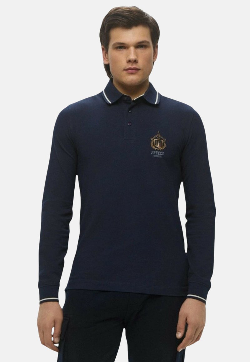 Polo a maniche lunghe colore blu navy con colletto, caratterizzato da accenti a strisce bianche e un emblema dorato sul petto. Realizzato in tessuto di misto cotone liscio.