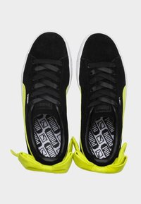 Baskets en suède noir avec des accents jaunes vifs, à lacets, et semelles intérieures à motifs. Bout rond et semelle en caoutchouc blanc flexible.