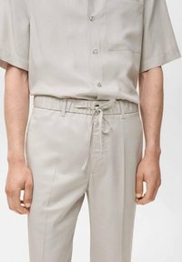 Light gray button-up shirt with short sleeves and a chest pocket, paired with matching elastic waist pants featuring a drawstring.