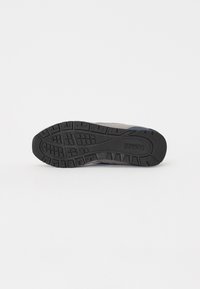 Black rubber sole with deep tread pattern and textured surface; gray textile upper with blue accents. Durable design for traction and support.
