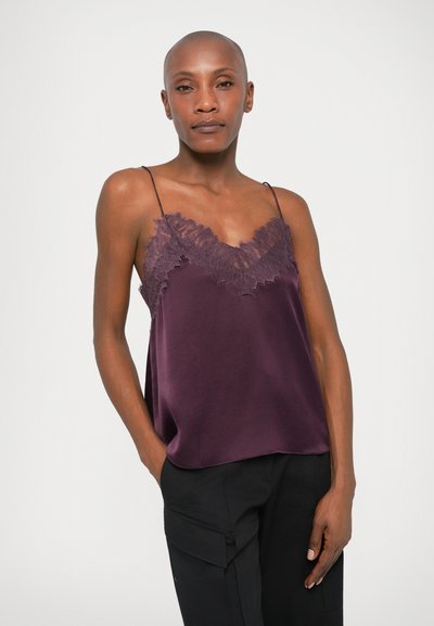 Lilla satenist camisole, millel on pitsäärisega kaelus ja õhukesed reguleeritavad rihmad. Sile tekstuur ja lõtv mugavus. Kombineeritud mustade pükstega.