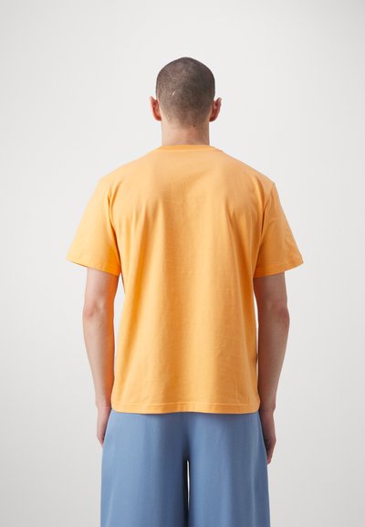 Kortermet t-skjorte laget av bomull i sterk orange. Har rund hals, avslappet passform og glatt tekstur. Baksiden vises.
