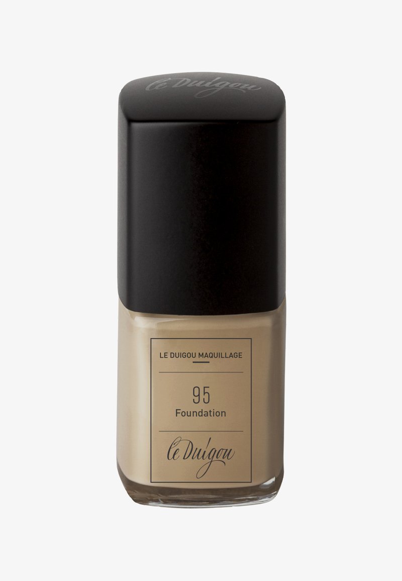 Flacon de fond de teint avec une base en verre carrée, liquide beige et un capuchon noir épuré. L'étiquette comprend "95 Foundation" et "le Duigou" dans une police élégante.