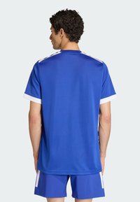 Modrý sportovní dres s bílými detaily, krátkými rukávy a volným střihem. Vyroben z lehké, strukturované tkaniny navržené pro pohodlí a volnost pohybu.