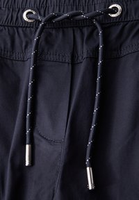Marina blå shorts med elastiskt midjeband, utrustade med en dragsko med metallspetsar och en enda sidoficka. Slät textur.