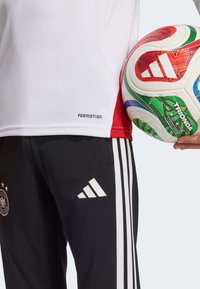 Biele a červené tričko s nápisom "FORMOTION", čierne nohavice s tromi bielymi pruhmi a logom Adidas, držiace farebnú futbalovú loptu.