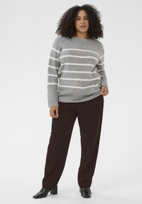 Pull rayé gris et blanc avec un ourlet côtelé, associé à un pantalon marron foncé et des bottines à talons noires. Texture lisse, coupe décontractée.