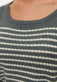 Pull rayé gris et blanc avec un décolleté en bateau et un tricot texturé. Les rayures alternent en épaisseur, avec une finition en tissu doux.