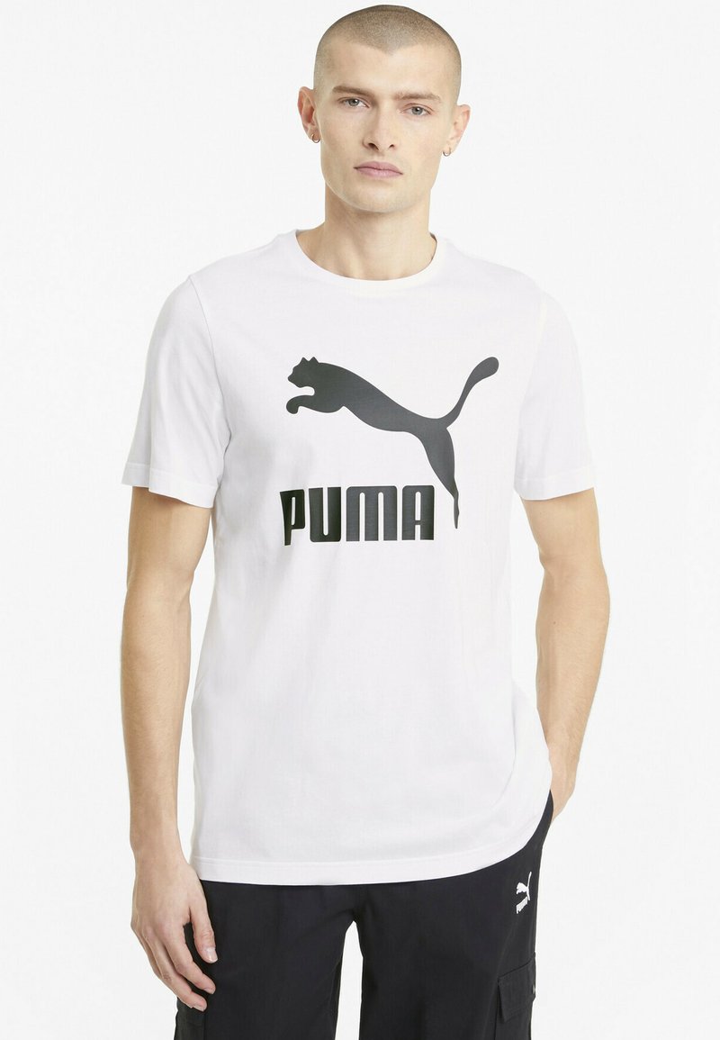 Hvid bomulds t-shirt med et stort sort Puma logo design. Kortærmet og rund hals med en afslappet pasform. Glat tekstur.