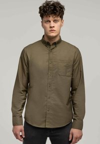 Olive zielona koszula zapinana na guziki, wykonana z teksturowanej tkaniny, z kieszenią na piersi, długimi rękawami i zaokrąglonym dołem. Zawiera subtelne detale w szyciu.