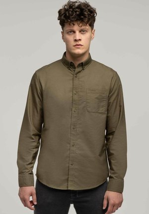Olive zielona koszula zapinana na guziki, wykonana z teksturowanej tkaniny, z kieszenią na piersi, długimi rękawami i zaokrąglonym dołem. Zawiera subtelne detale w szyciu.