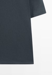 Mørkegrå t-shirt med korte ærmer, lavet af glat bomuldsstof, med rund halsudskæring og en enkel, afsluttet kant.