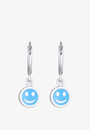 Boucles d'oreilles argentées en crochet avec des pendentifs ronds en forme de visage souriant bleu ornés de détails blancs. Les pendentifs pendent sous l'oreille avec une finition lisse.