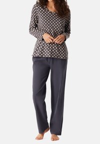 Långärmad topp i marinblått med beige geometriskt mönster, ihop med lösa grå byxor. Mjuk tygkvalitet med avslappnad passform och rundad halsringning.