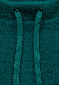 Türkisfarbener, plüschiger Stoff mit weicher Textur, ausgestattet mit zwei passenden flachen Kordeln. Es sind keine sichtbaren Beschläge oder Muster vorhanden.