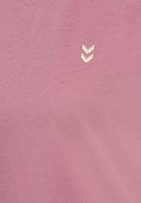 Rosa Kurzarmhemd mit glatter Textur, mit einem kleinen weißen Chevron-Logo auf der Vorderseite. Leichter Stoff, der sich für Freizeitkleidung eignet.