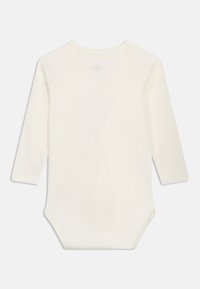 Απλό, μακρυμάνικο βρεφικό φορμάκι σε εκρού χρώμα με στρογγυλή λαιμόκοψη και κλείσιμο με κουμπιά στο κάτω μέρος, εμφανιζόμενο από πίσω.