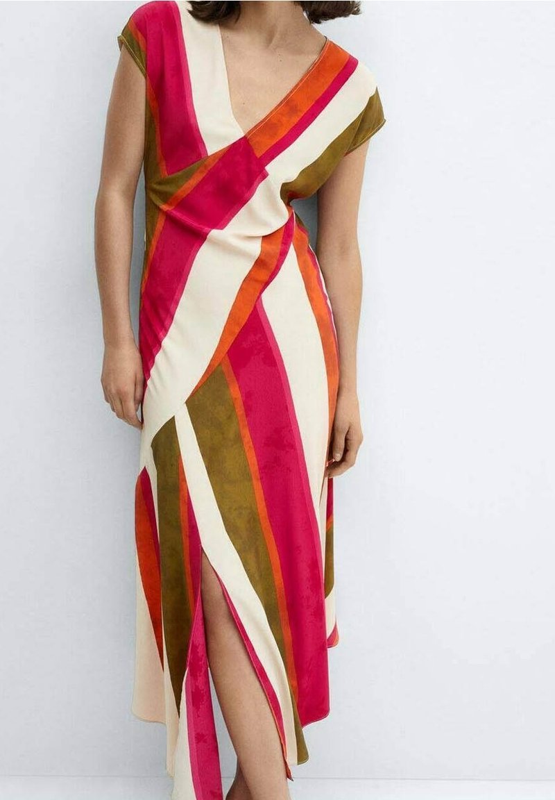 Femme portant une robe portefeuille sans manches à rayures diagonales rose, orange, vert olive et crème, avec une fente à l'avant laissant entrevoir sa jambe.