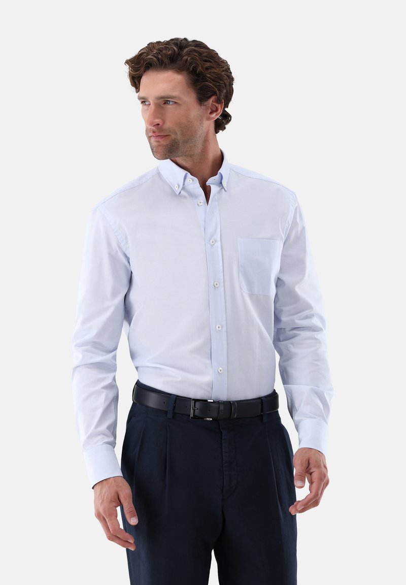 Hellblaues Hemd mit Knöpfen, Kragen, einer Brusttasche und langen Ärmeln, kombiniert mit einer dunklen Hose und einem schwarzen Gürtel.