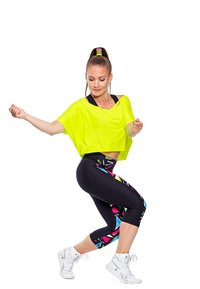 Top scurt de culoare galben neon cu mâneci scurte, asortat cu colanți negri până la genunchi cu modele geometrice multicolore; adidași albi.