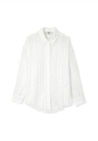 Chemise blanche à manches longues et boutons, avec un tissu texturé présentant des rayures verticales et des détails froncés le long des coutures et du col.