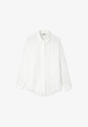Chemise blanche à manches longues et boutons, avec un tissu texturé présentant des rayures verticales et des détails froncés le long des coutures et du col.