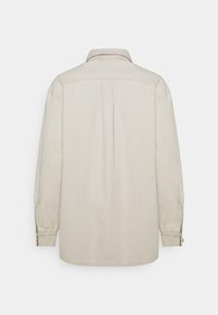 Chemise beige à manches longues avec col, poignets boutonnés et coupe droite ; fabriquée dans un tissu lisse et léger.