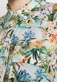 Kortärmad, knapp-up skjorta i lätt tyg med ett livligt blommigt och tropiskt mönster i grönt, blått och gult.