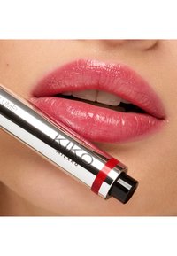 Lśniący różowy kolor szminki na pełnych ustach, z metaliczną tubką szminki w kolorze srebrnym z czerwonymi akcentami oraz widoczną nazwą marki "KIKO MILANO".