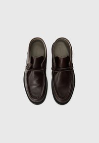 Bruna läderskjortor i slip-on stil med rundad tå, tjock svart gummisula och dekorativ söm längs kanterna.