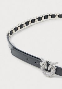 Cintura in pelle nera con accenti di catena argentata, dotata di una fibbia decorata con strass a forma di due uccelli. Texture liscia, vestibilità regolabile.