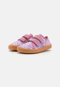 Chaussures en tissu rose avec des motifs floraux et en forme de cœur, dotées de deux bandes Velcro réglables et d'une semelle en caoutchouc beige.