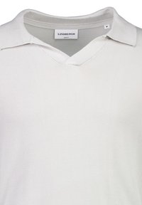 Biały, dopasowany sweter z dekoltem w kształcie litery V i złożonym kołnierzem. Wykonany z miękkiego materiału, ma czystą, gładką fakturę i minimalne zdobienia.