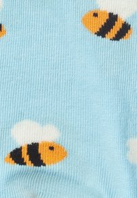 Hellblauer Stoff mit einem Strickmuster aus orangefarbenen und schwarzen Bienen, einige mit weißen Flügeln, gleichmäßig über das Material verteilt.