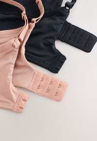 Zwei weiche Stoff-BHs, einer hellrosa und einer schwarz, die eine Nahaufnahme von verstellbaren Haken- und Ösenverschlüssen auf neutralem Hintergrund zeigen.