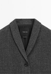 Blazer en laine texturée gris foncé avec col à revers cranté et un seul bouton noir, étiqueté Massimo Dutti, fabriqué au Maroc.
