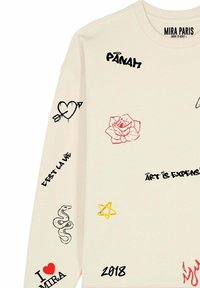 Sudadera de color beige claro con varios gráficos impresos, incluyendo una rosa, un corazón, una serpiente y texto. Los colores del texto incluyen acentos en negro y rojo.