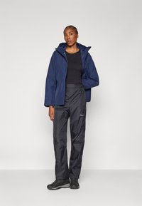 Navy waterproof jacket with a hood, paired with black waterproof pants and sturdy black footwear. Smooth fabric, practical design, and functional features.