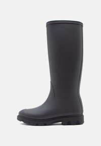 Black rubber knee-high boot with a smooth texture, rounded toe, and rugged sole featuring deep treads for traction.