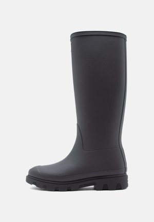 Black rubber knee-high boot with a smooth texture, rounded toe, and rugged sole featuring deep treads for traction.