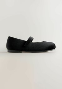 Scarpa piatta Mary Jane nera realizzata in morbido suede, con punta rotonda, una strap in velcro a metà piede e suola nera testurizzata.