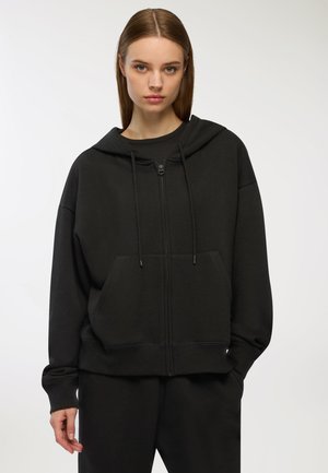 Felpa nera con zip e cappuccio, tasche frontali e lacci. Tessuto morbido, vestibilità ampia, polsini e orlo a coste. Design semplice e uniforme.