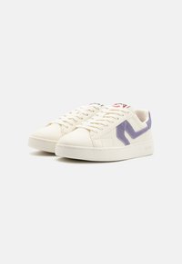 White sneakers made of leather featuring a purple lateral stripe, rounded toe, and flat sole. Color-accented branding on the tongue.