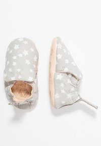 Zapatos de bebé de cuero gris con un patrón de estrellas blancas, suaves tobillos elásticos para facilitar el uso y suelas de goma rosadas con ligera textura.