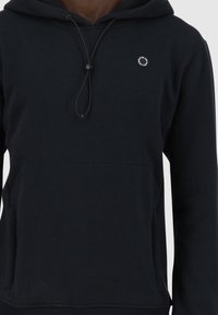 Hoodie noir en mélange de coton, avec une poche frontale, une capuche ajustable à cordon et un petit logo circulaire sur la poitrine.