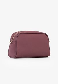 Borsa cosmetica bordeaux di forma rettangolare, con finitura liscia e zip dorata. Presenta bordi arrotondati e un design minimalista.