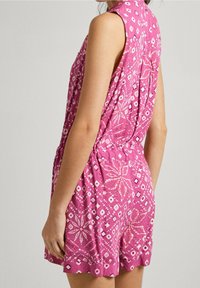 Ärmlös rosa jumpsuit med blommönster och diamantmönster. Har en avslappnad passform, elastisk midja och texturerad tyg.