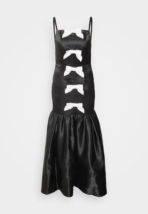 Zwarte satijnen jurk met witte strikdetails, dunne bandjes, een aansluitend lijfje en een uitlopende, gerimpelde zoom. Soepele textuur en klassiek ontwerp.
