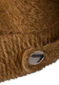 Faux fur product in bruin met een zachte, gestructureerde oppervlakte en een grote metalen drukknoopaccent, die het fluffy ontwerp benadrukt.