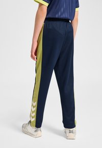 Granatowe sportowe spodnie dresowe z limonkowozielonymi bocznymi panelami i wzorem strzałek, elastycznym pasem i gładką, elegancką teksturą.